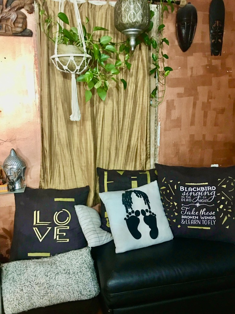 before pictures of the bed with a wrinkled dark comforter, pillows and a multi color crochet afghan and the black leather ottoman with sever throw pillows. 