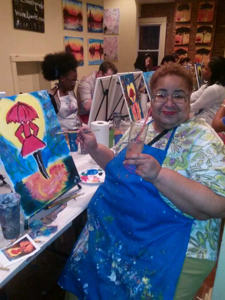 my mom enjoying a drink at the paint and sip while painting a woman with an umbrella