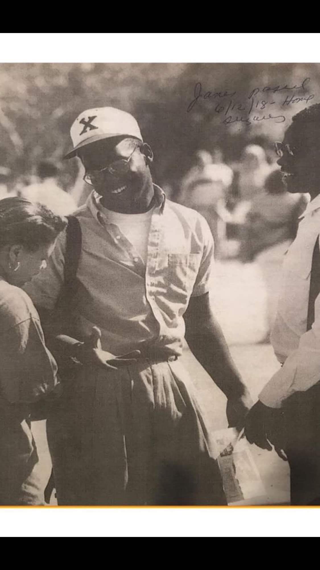 Black and white photo of a young man talking to friends on college campus